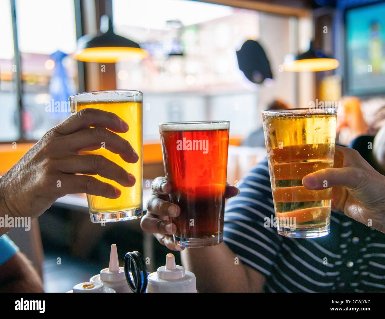 Group of friends having fun in a pub holding beer glasses. Stock Photo