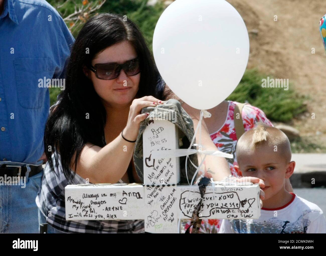 Rebecca Diercks touches the cross for family friend Air Force Staff Sergeant Jesse Childress at a memorial near the movie theater where Childress and 11 other people where killed last Friday in Aurora, Colorado July 23, 2012. REUTERS/Rick Wilking (UNITED STATES - Tags: DISASTER CRIME LAW) Stock Photo