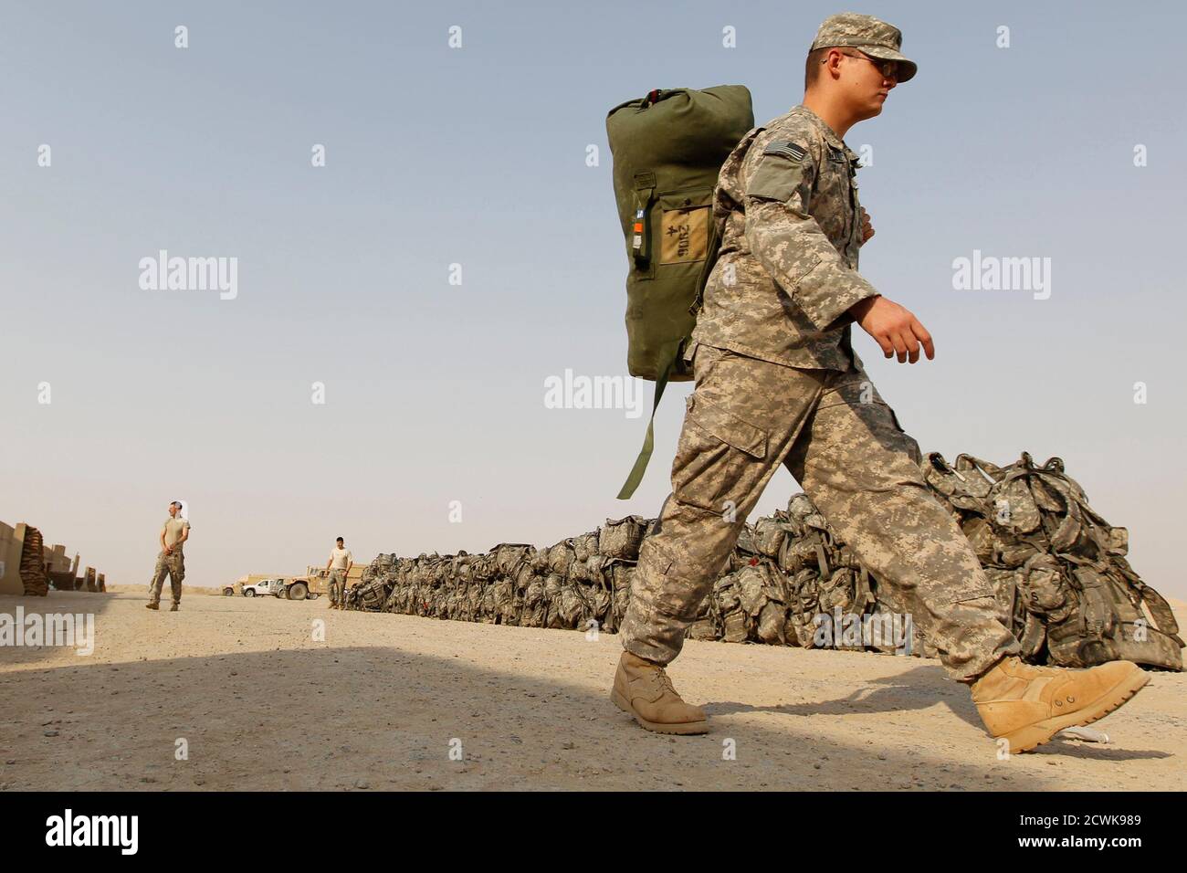 A U.S. soldier from the 1st Battalion,116th Infantry Regiment, carries his bag as he prepares to pull out from Iraq to Kuwait, at Tallil Air Base near Nassiriya, 300 km (185 miles) southeast of Baghdad, August 15, 2010.  Picture taken August 15, 2010.  REUTERS/Thaier al-Sudani (IRAQ - Tags: CONFLICT POLITICS) MILITARY) Stock Photo
