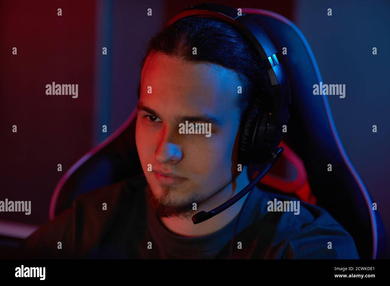 Young computer programmer in headphones working on computer in dark office Stock Photo