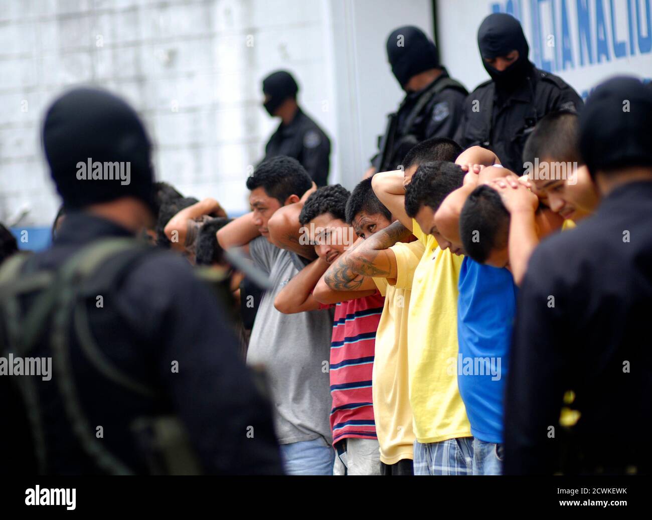 Policemen escort gang members of Mara Salvatrucha (MS13), who were detained during a night raid, in Soyapango, on the outskirts of El Salvador June 21, 2012. At least 30 of the 160 gang members arrested during a raid late Wednesday were presented to the media by the National Civil Police (Policia Nacional Civil, PNC), local media reported. According to the government of El Salvador, since a truce was signed between MS13 and 18 gangs, daily crimes have dropped from 15 cases to five. REUTERS/Ulises Rodriguez (EL SALVADOR - Tags: CRIME LAW) Stock Photo