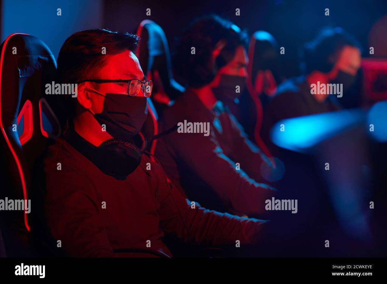 Group of computer programmers in protective masks using computers in their work in dark office Stock Photo