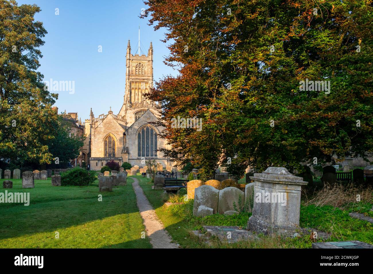 The Church of St. John the Baptist from the garden of rememberance at sunrise in autumn. Cirencester, Cotswolds, Gloucestershire, England Stock Photo