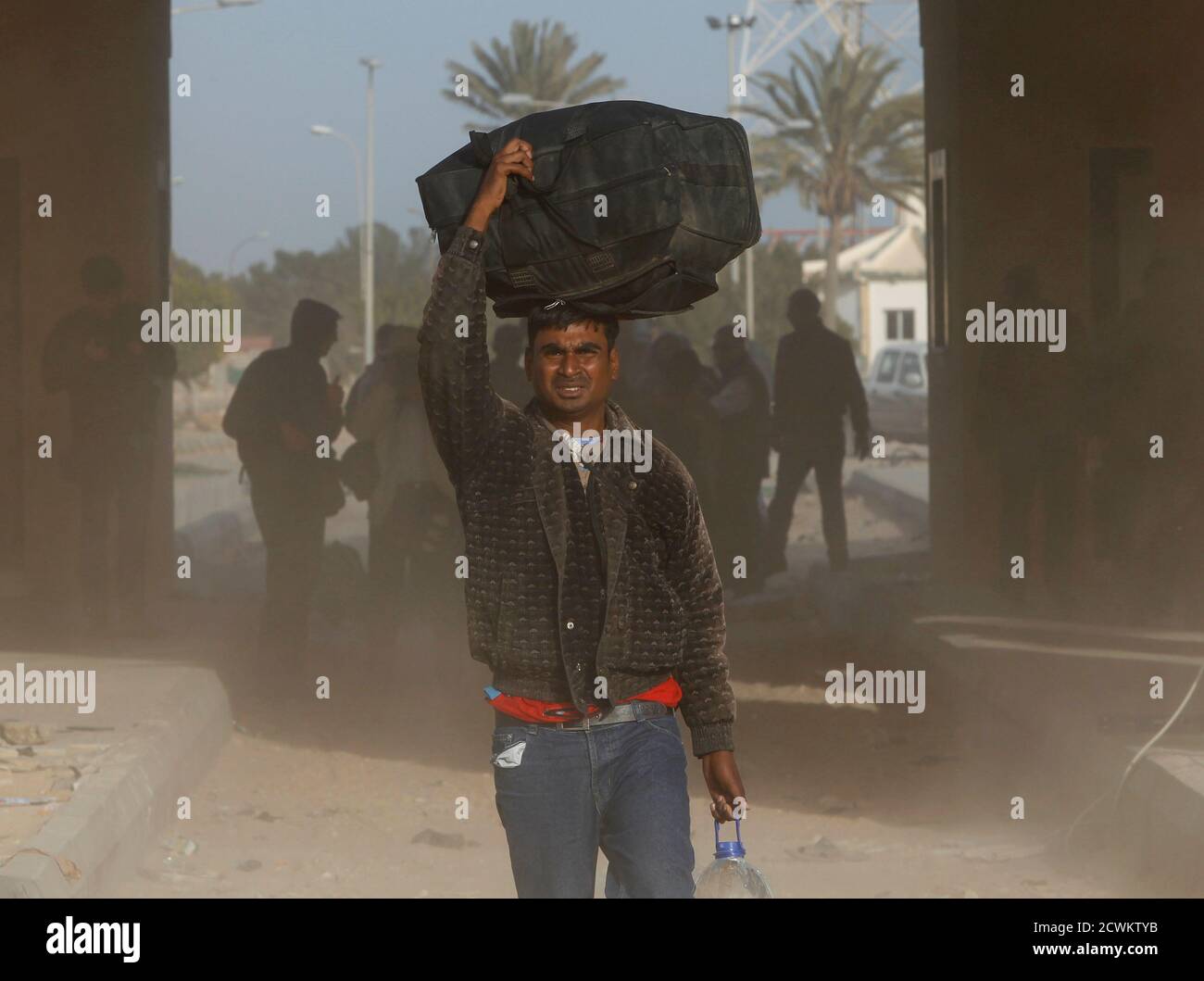 EDITOR'S NOTE: PICTURE TAKEN ON GUIDED GOVERNMENT TOUR  A foreign worker crosses the frontier to Tunisia, at a border point in Ras Judeir, Libya March 3, 2011. REUTERS/Ahmed Jadallah       (LIBYA - Tags: POLITICS CIVIL UNREST) Stock Photo
