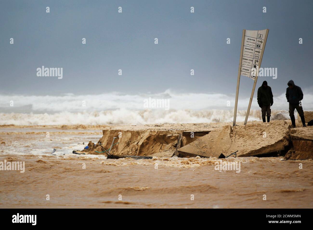 People look on the damage caused by a storm on a beach of the Mediterranean sea near Kibbutz Nitzanim December 13, 2013. A snowstorm of rare intensity blanketed the Jerusalem area and parts of the occupied West Bank on Friday, choking off the city and stranding hundreds in vehicles on impassable roads. REUTERS/Amir Cohen (ISRAEL - Tags: ENVIRONMENT) Stock Photo