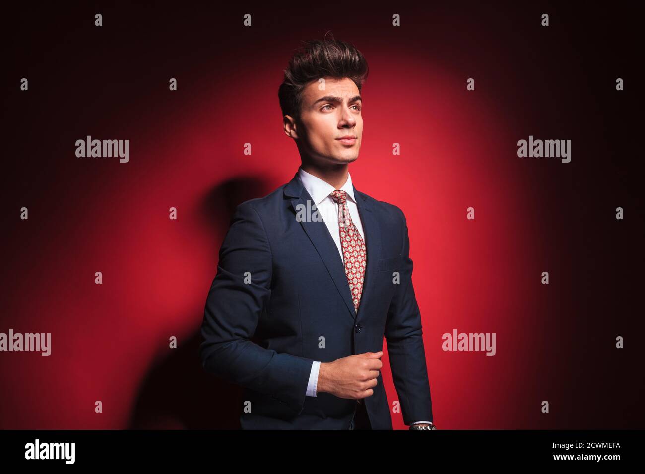 portrait of confident young businessman in black suit with red tie ...