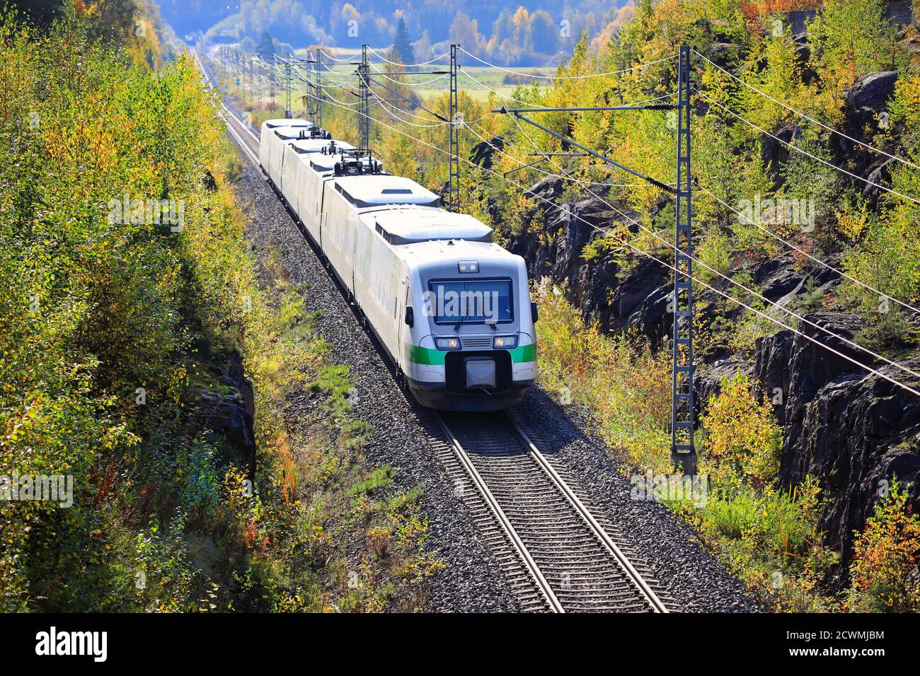 Express train travelling through autumnal scenery in Finland on a beautiful day, elevated view. Stock Photo