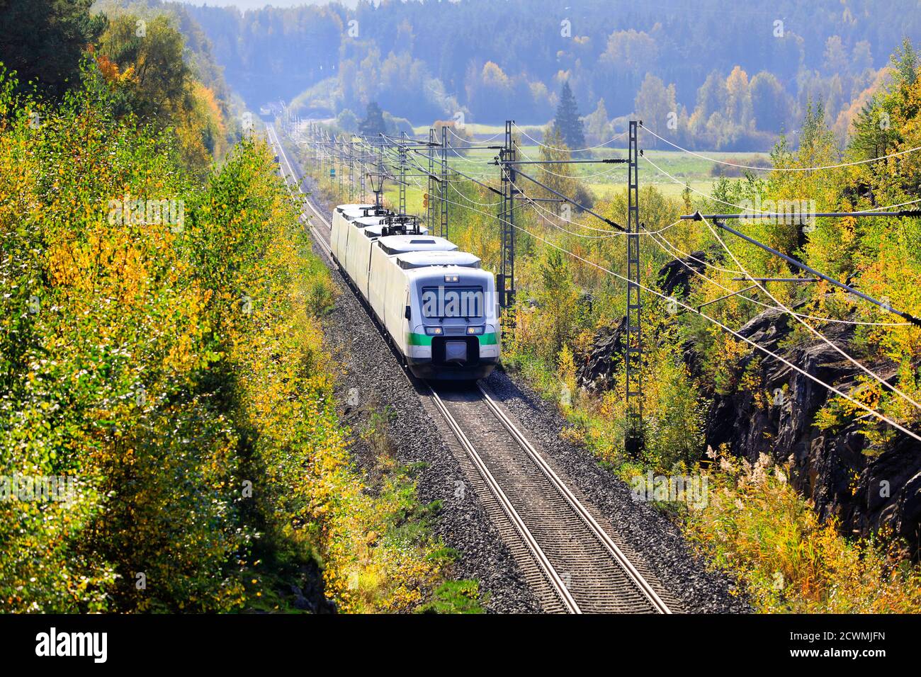 Express train travelling through autumnal scenery in Finland on a beautiful day, elevated view. Stock Photo