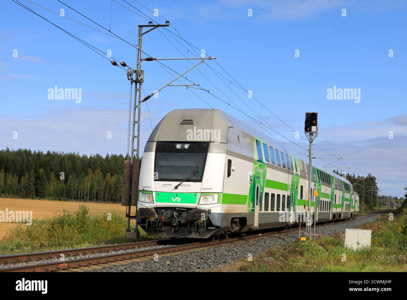 Modern VR Group Intercity electric 2 storey passenger train on the move at rural railroad crossing. Humppila, Finland. September 18, 2020. Stock Photo