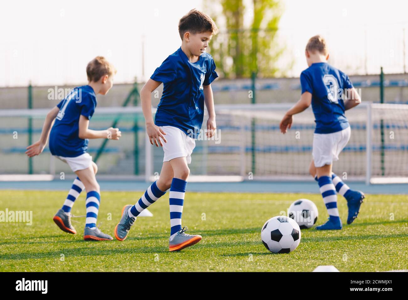 Junior Football Players Making Sports Training, Happy Boys on Soccer Practice Session on Summer Time. School Sports Stadium in the Background Stock Photo