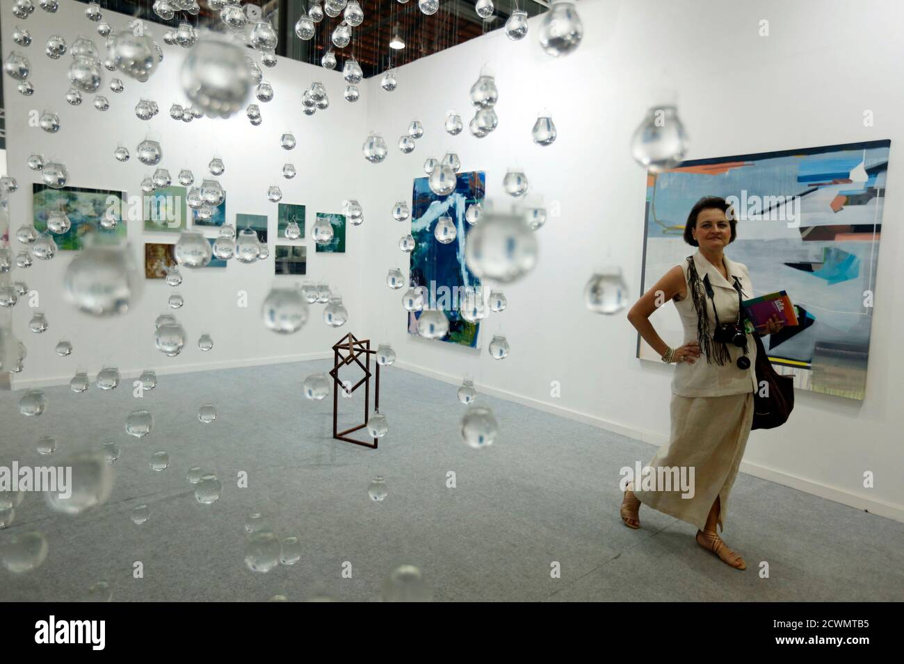 A woman walks next to lightbulbs filled with water as part of the 