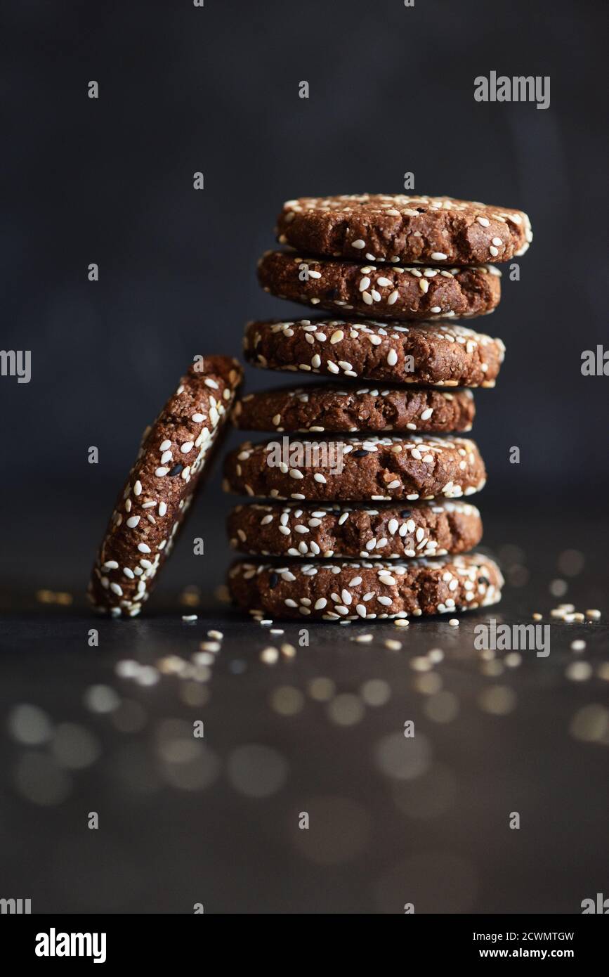 Vegan gluten free chocolate cookies with white and black sesame seeds on black background side view copy space Stock Photo