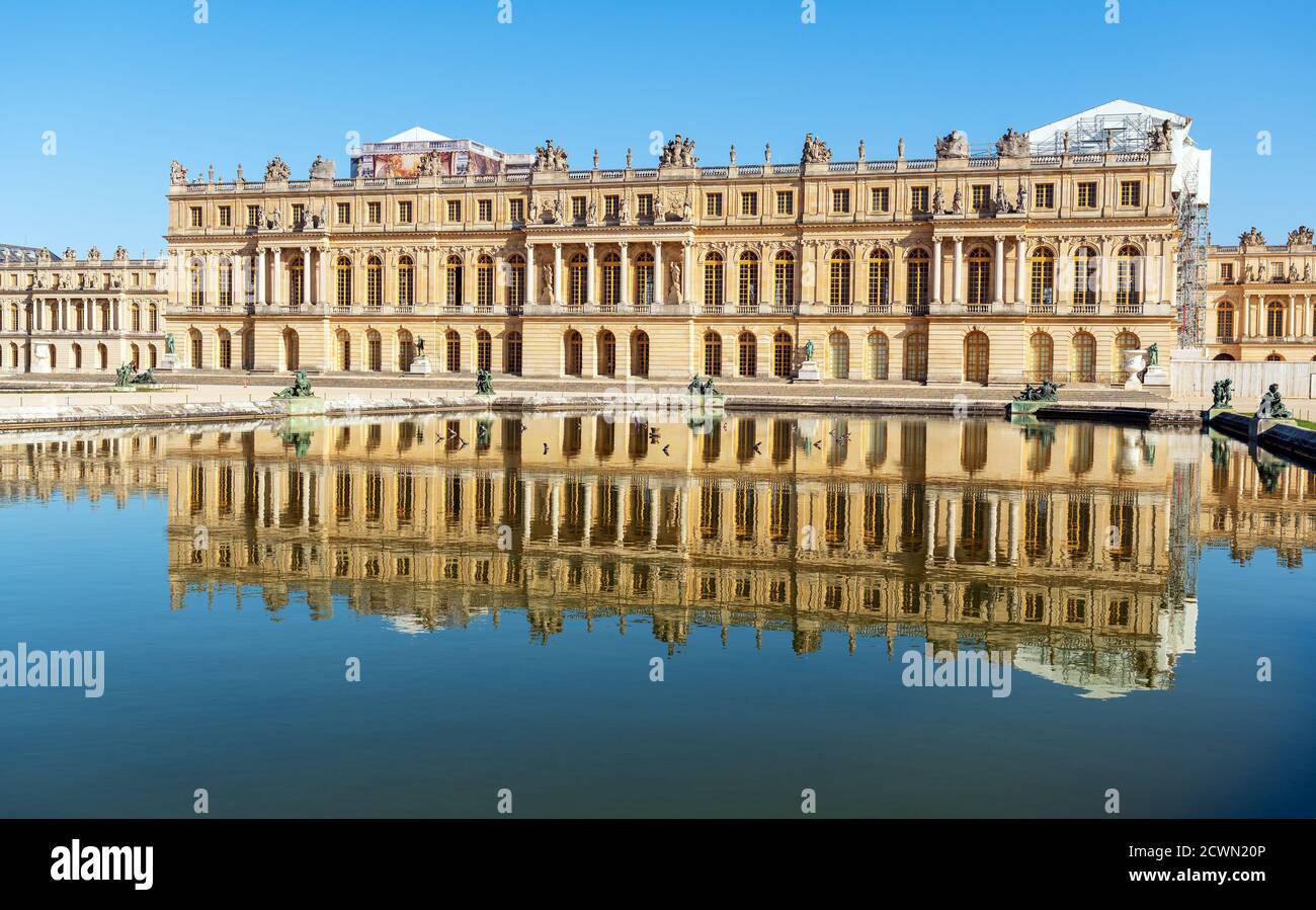 Reflection of Versailles palace facade in a pond at golden hour - France Stock Photo