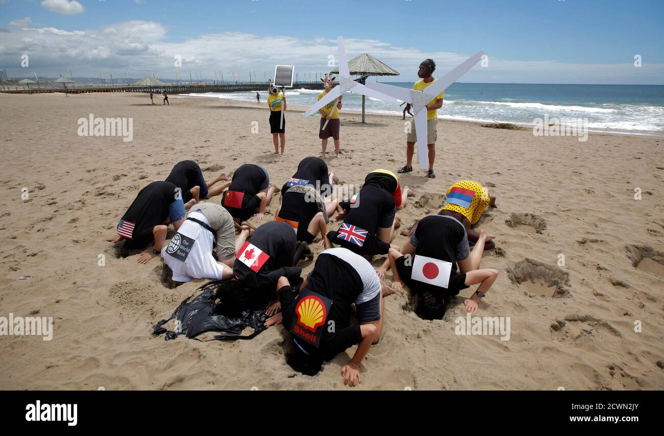 Environmental activists with flags on their backs bury their heads in the sand on Durban's beachfront, December 2, 2011. The demostration aimed to highlight nations failing to act effectively to prevent climate change. The city is hosting the United Nations Climate Change conference (COP17).   REUTERS/Mike Hutchings (SOUTH AFRICA - Tags: ENVIRONMENT POLITICS CIVIL UNREST TPX IMAGES OF THE DAY) Stock Photo