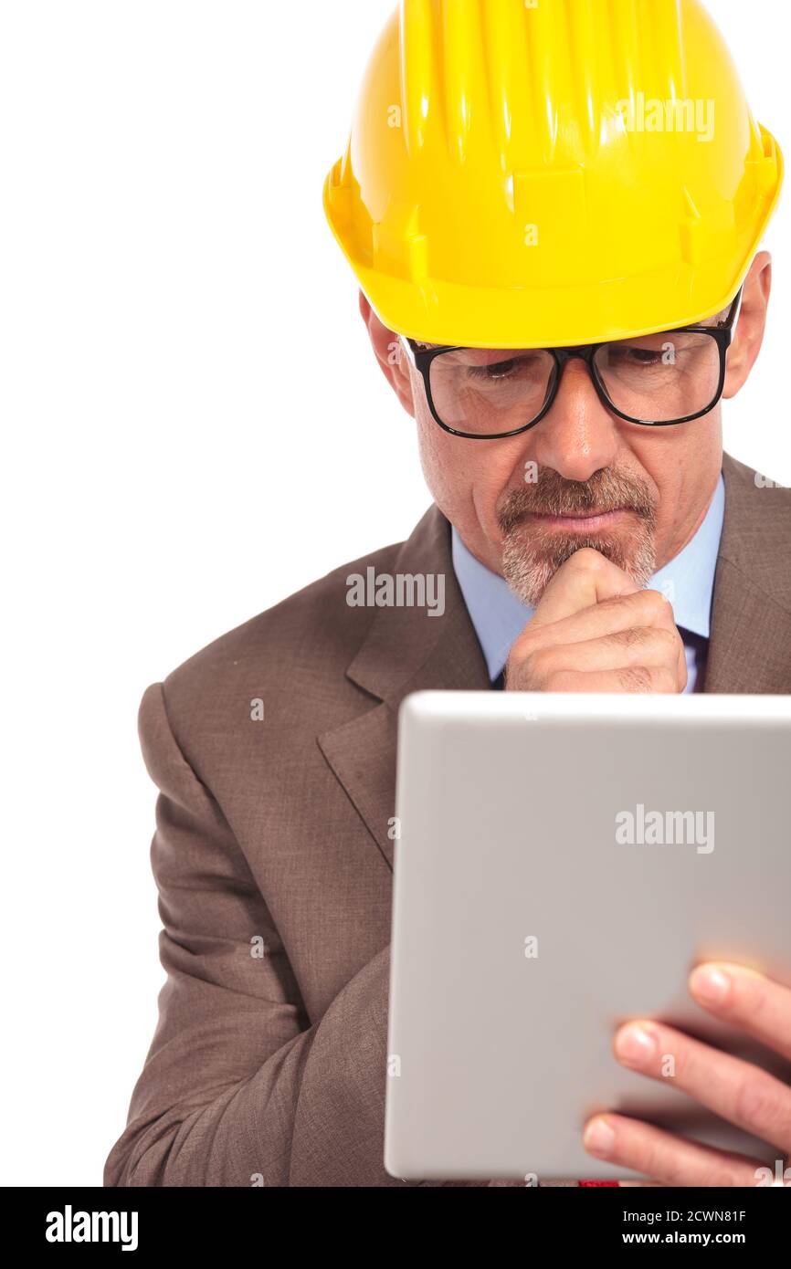 thoughtful construction engineer reading on his tablet pad on white background Stock Photo