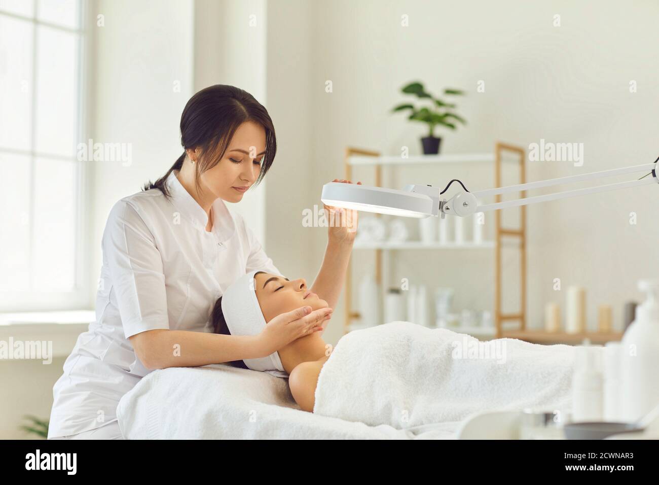 Smiling dermatologist looking at young womans face during skin examination Stock Photo