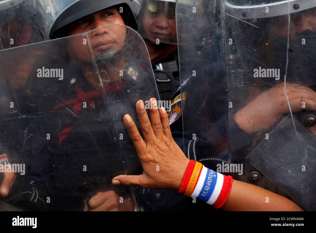 An anti-government protester pushes against riot policemen at a barricade near the Government House in central Bangkok February 14, 2014. Thousands of Thai riot police were deployed on Friday to seize back protest sites around government buildings in Bangkok that have been occupied for months by demonstrators seeking to topple Prime Minister Yingluck Shinawatra. REUTERS/Damir Sagolj (THAILAND - Tags: SOCIETY CIVIL UNREST) Stock Photo