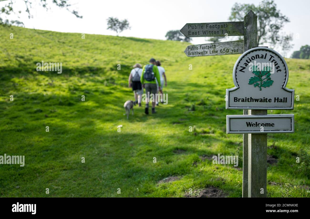 Walkers walking along a public footpath in the National Trust property of Braithwaite Hall, Yorkshire Dales. Stock Photo