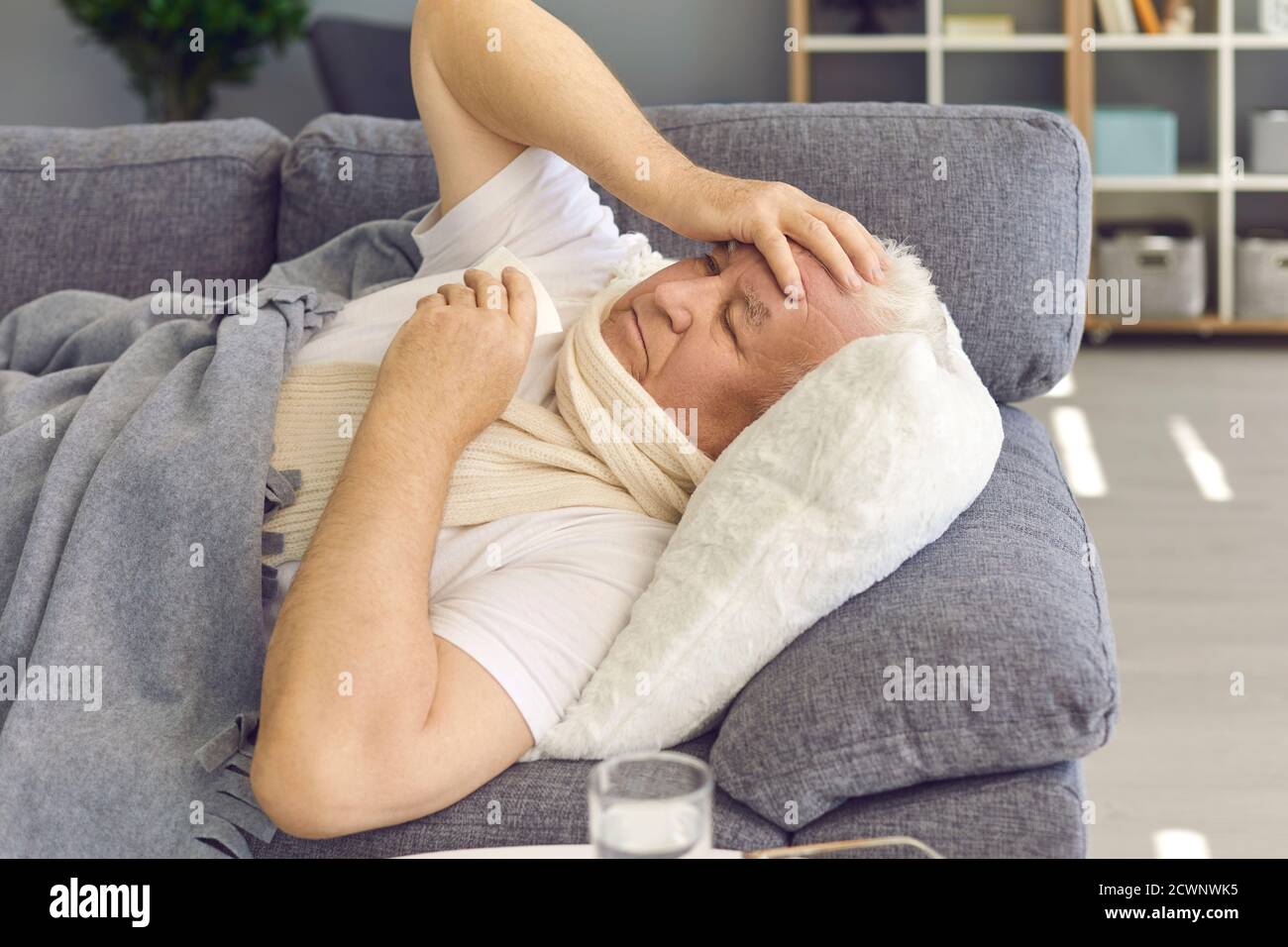 Sick senior man suffering from bad cold, flu or covid fever, coughing and having runny nose Stock Photo