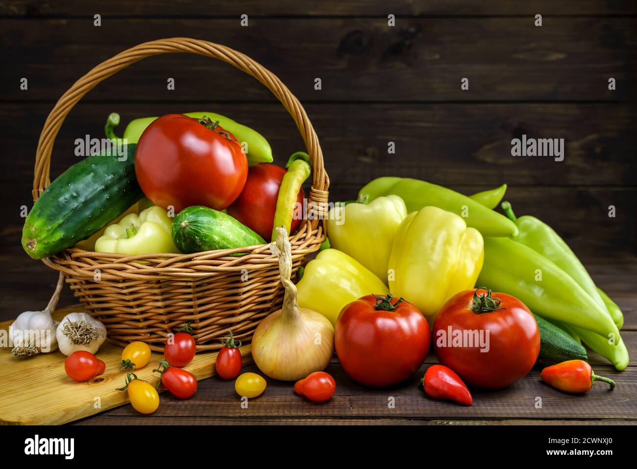 Composition with various fresh vegetables and wicker basket on a wooden table. Stock Photo