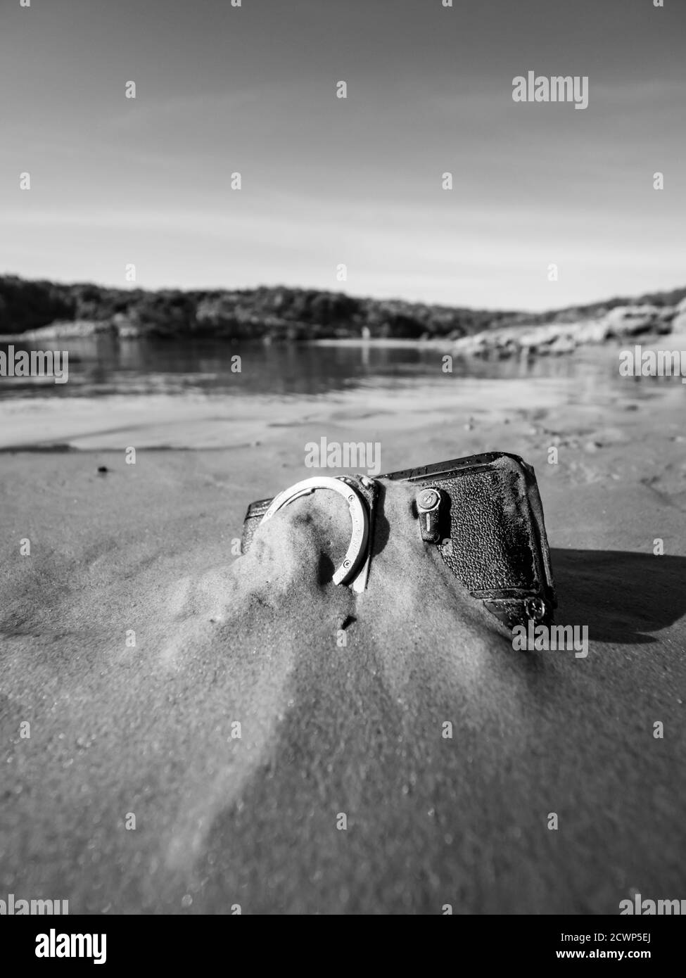 Nikon retro classic SLR film camera body on beach inverted upside down upsidedown calm calmness smooth serenity serene water surface Stock Photo