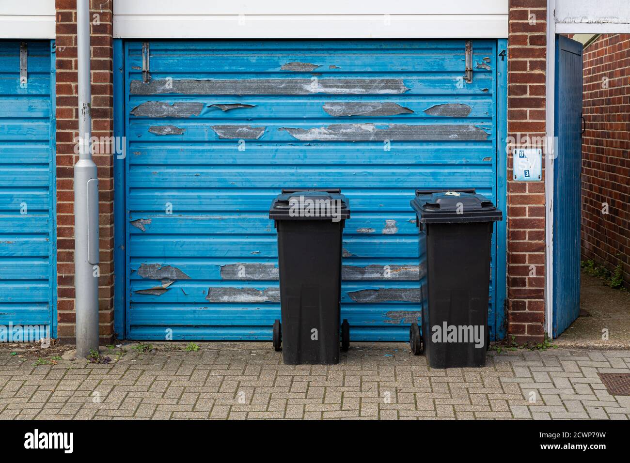 Two black wheelie bins outside the garage of a home awaiting collection