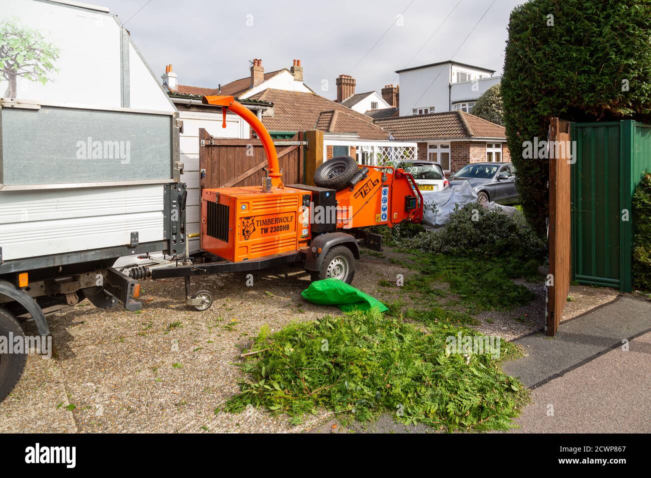 A wood chipper machine being used in the garden of a home by a tree surgeon Stock Photo