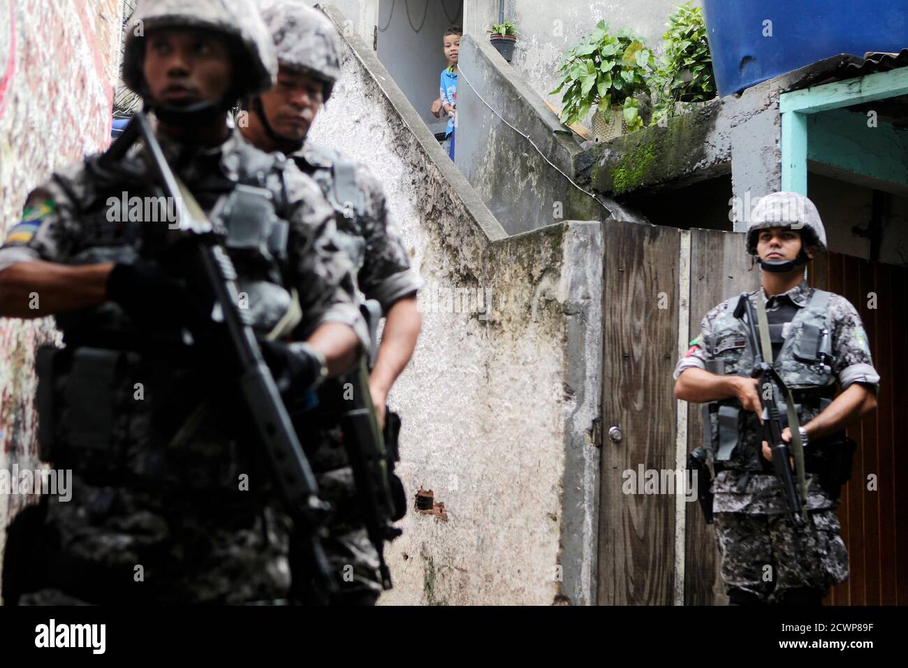 A boy looks on as Brazilian National Force policemen take part in an  operation against drugs in Santo Amaro slum in Rio de Janeiro May 18, 2012.  The Brazilian National Force is