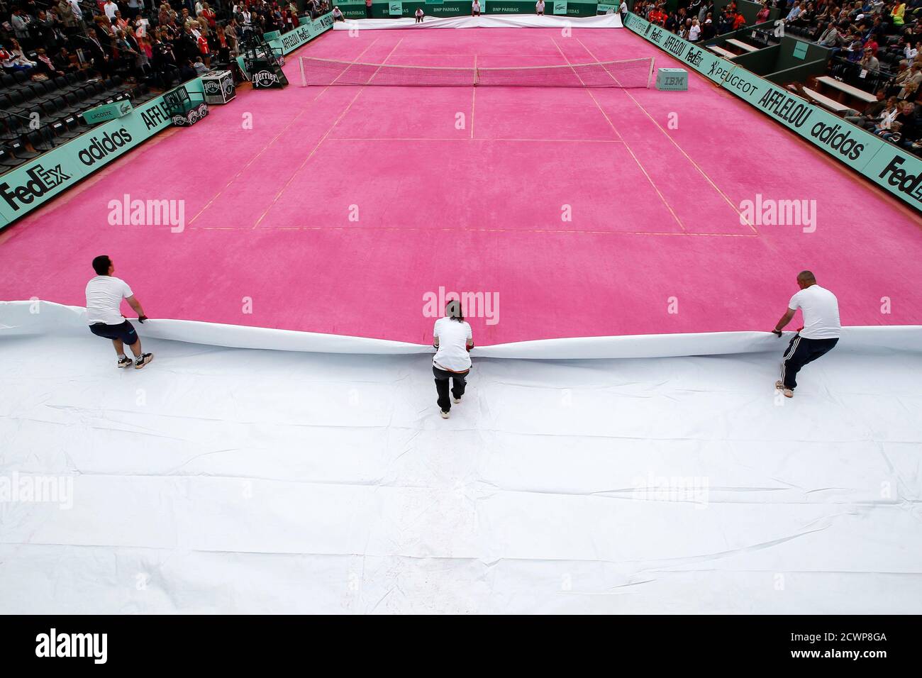 Court workers uncover an ephemeral pink clay court to celebrate Women's Day  during the French Open tennis tournament at the Roland Garros stadium in  Paris June 7, 2012. REUTERS/Regis Duvignau (FRANCE -