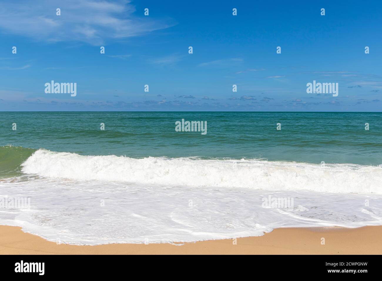 Sandy beach with sea waves and blue sky background Stock Photo - Alamy