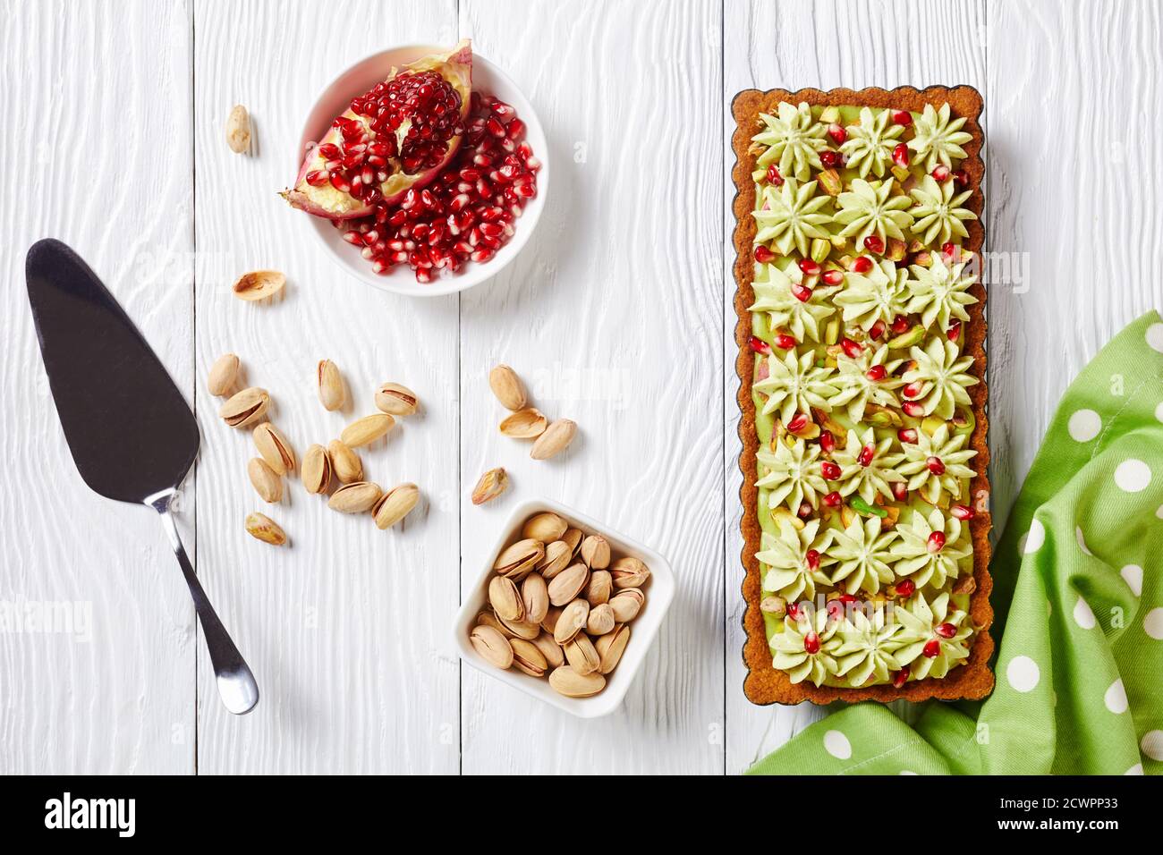 Pistachio ganache tart with pomegranate seeds on a square baking tin