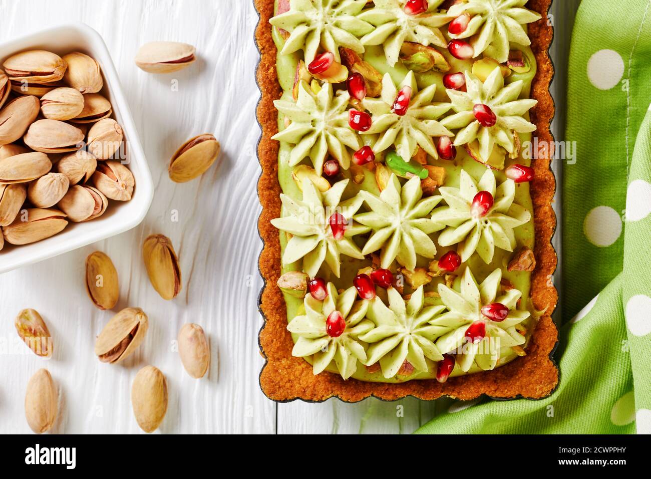 Pistachio ganache tart with pomegranate seeds on a square baking tin