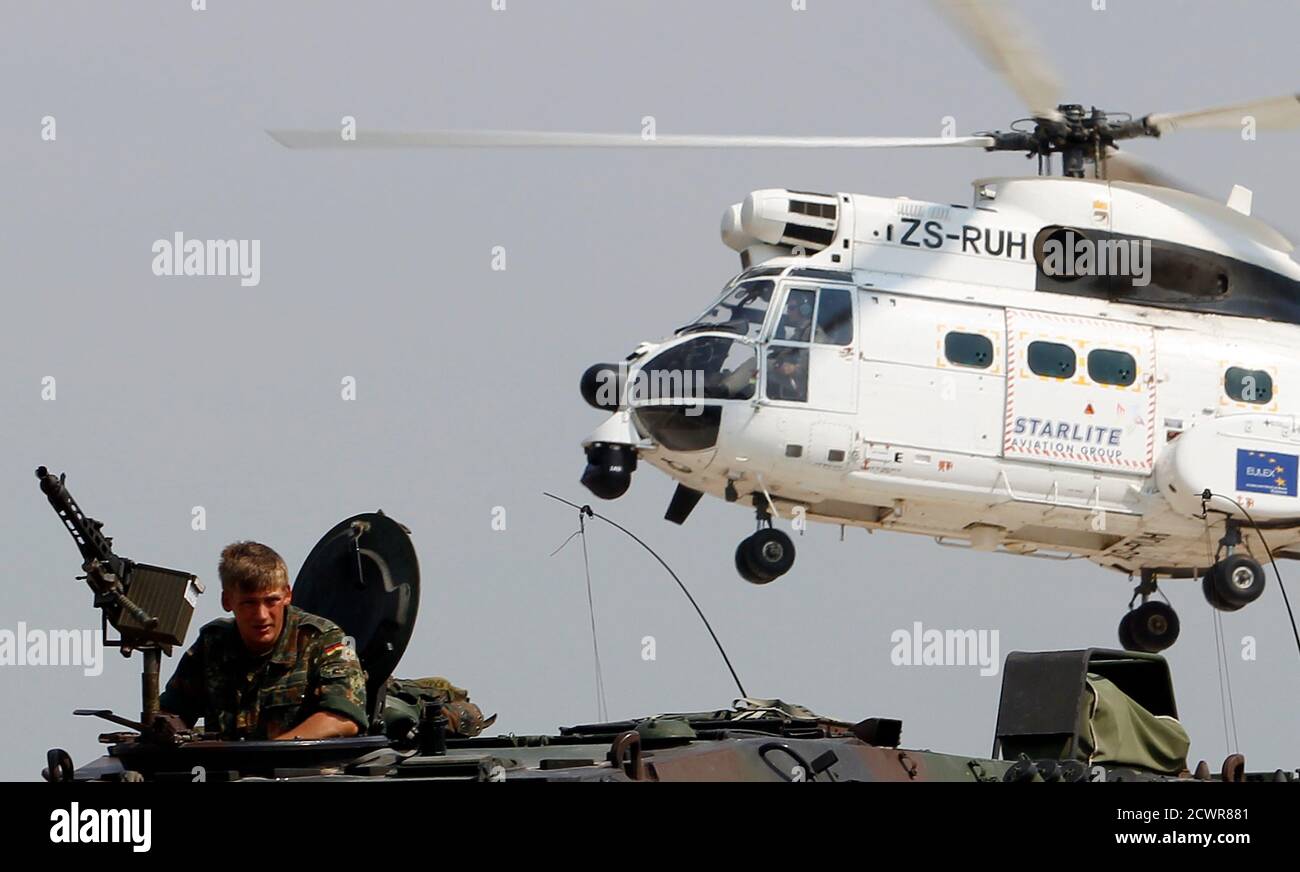 A Kosovo Force (KFOR) soldier from Germany sits in a TPz Fuchs armoured  personnel carrier (APC) as an Aerospatiale SA-330J Puma helicopter takes  off at the closed Serbia-Kosovo border crossing of Jarinje