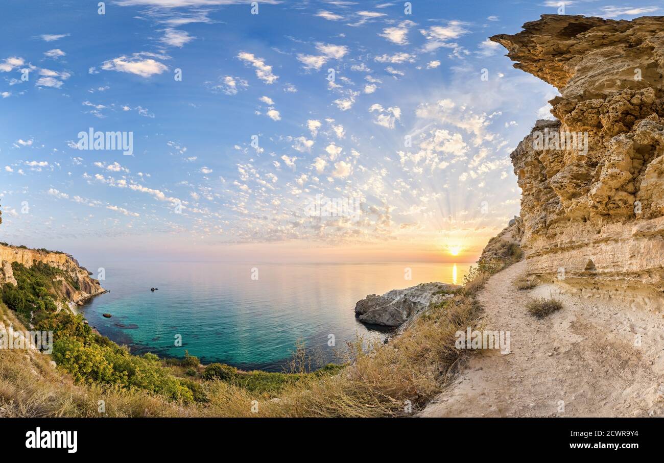 panorama on sunset time with beautiful clouds in the rocky bay with crystal clear azure sea on a sunny day. The concept of an ideal place for summer Stock Photo