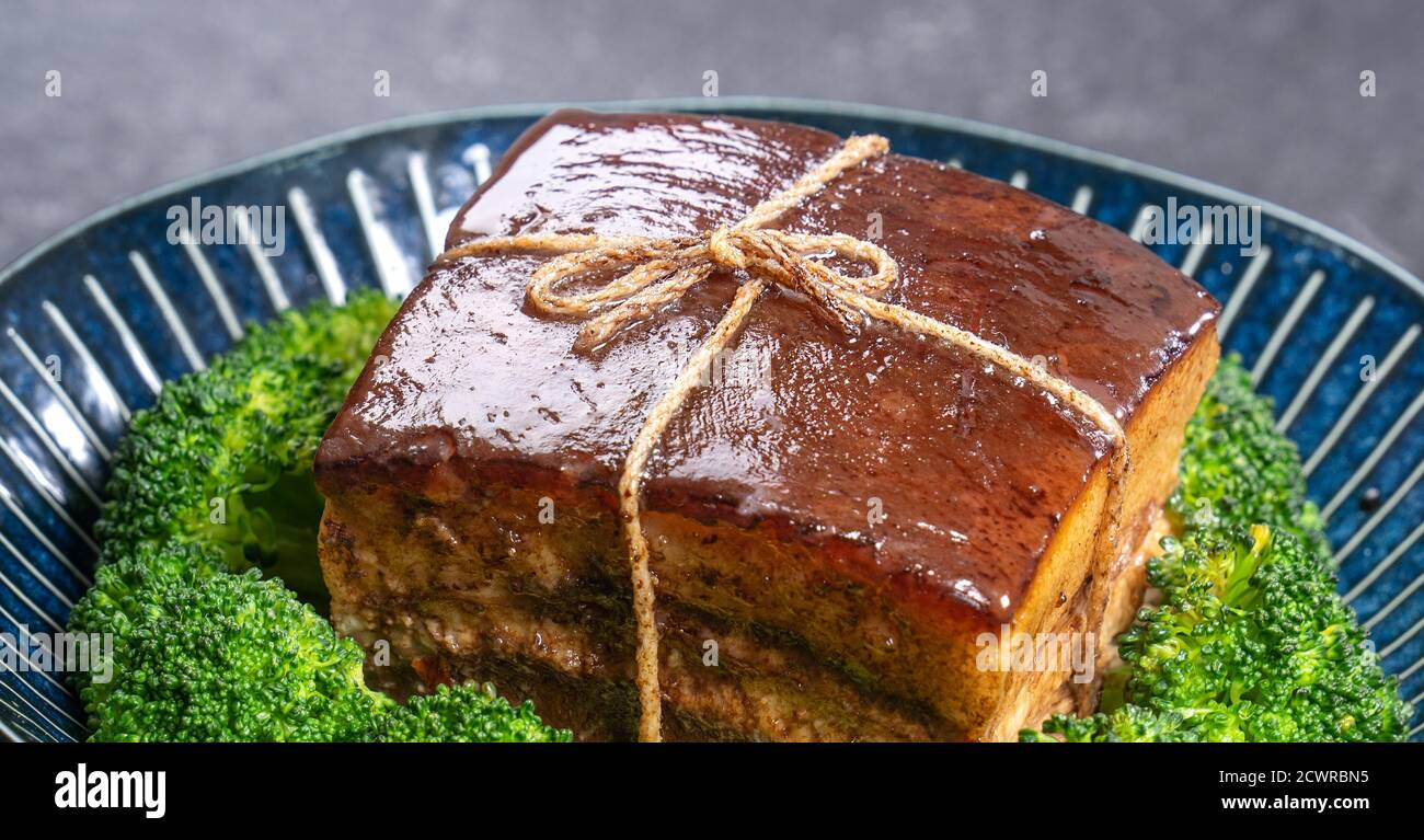 Dong Po Rou (Dongpo pork meat) in a beautiful plate with green vegetable, traditional festive food for Chinese new year cuisine meal, close up. Stock Photo