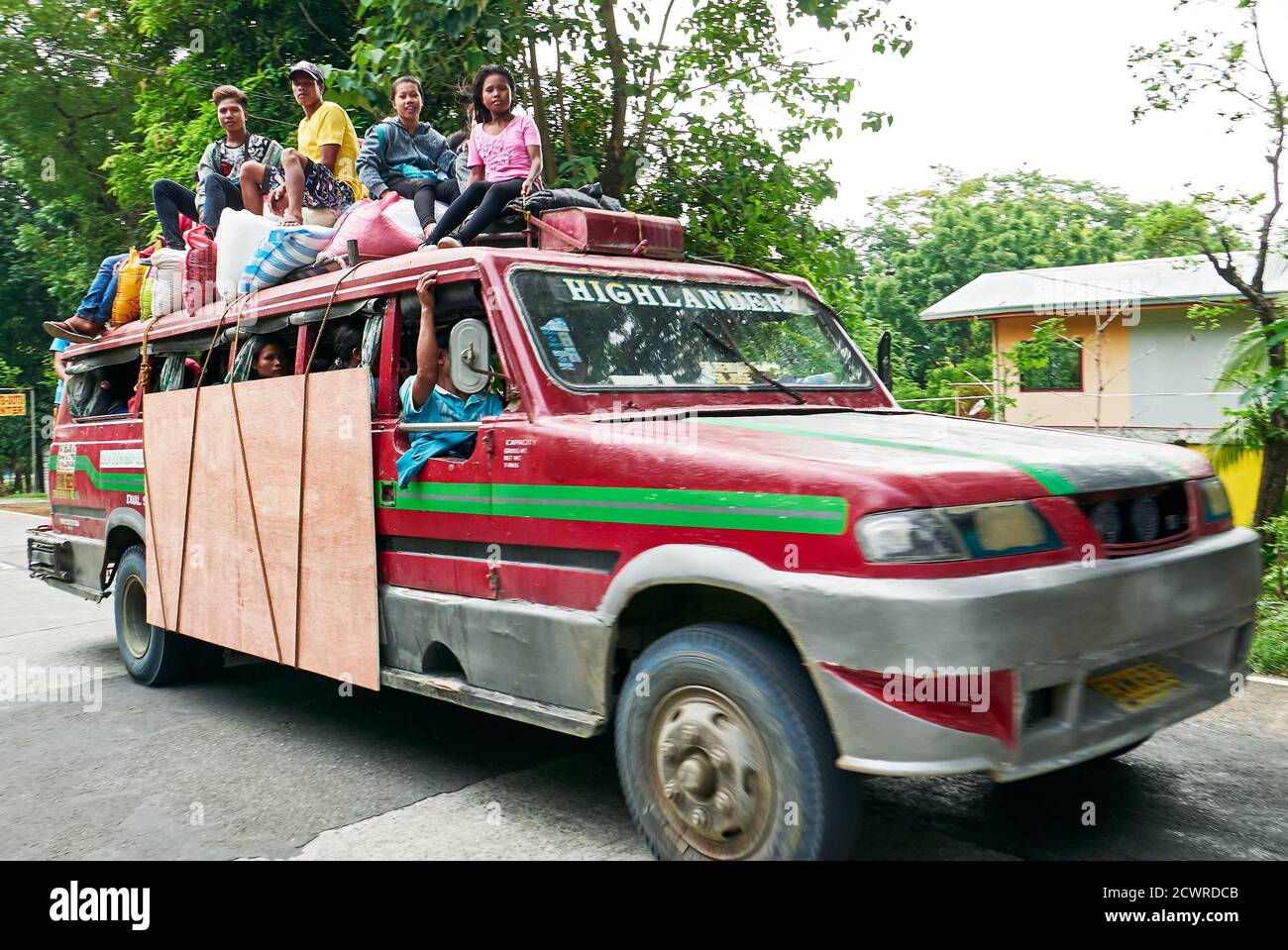 An old colorful philippine jeepney style truck with young people sitting on the roof together with rice sacks, Antique, Visayas, Philippines, Asia Stock Photo