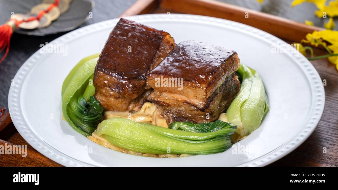 Dong Po Rou (Dongpo pork meat) in a beautiful plate with green vegetable, traditional festive food for Chinese new year cuisine meal, close up. Stock Photo