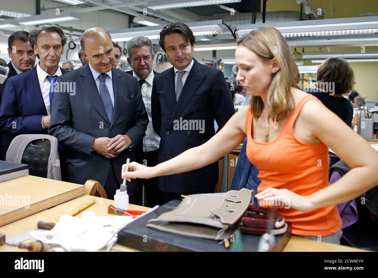 French Finance Minister Pierre Moscovici (2ndL) and Axel Dumas (2ndR),  co-chief executive of French luxury goods group Hermes, meet employees who  work on handbags as they visit the Hermes factory in Seloncourt