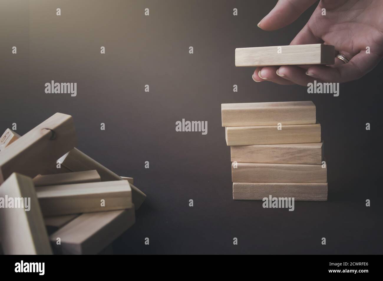 Hand hold a wooden block under stack of the same blocks. Business