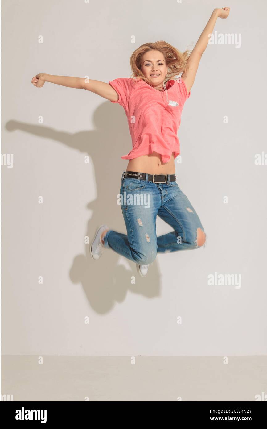 Happy young woman jumping with both hands in the air Stock Photo - Alamy