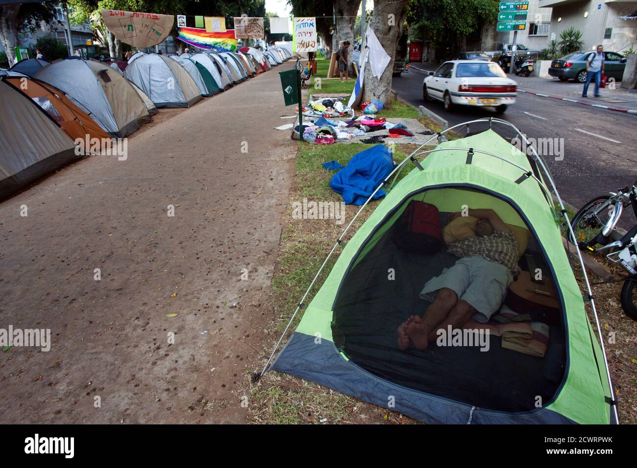 An Israeli protester sleeps inside his tent pitched on Tel Aviv's Rothschild Boulevard as he takes part in a demonstration against high housing prices, July 18, 2011. Similar protests have been planned in other Israeli cities where rental costs have skyrocketed as a result of a shortage in available dwellings in primary locations. REUTERS/Nir Elias (ISRAEL - Tags: POLITICS BUSINESS SOCIETY) Stock Photo