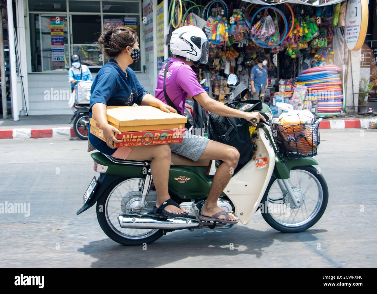 SAMUT PRAKAN, THAILAND, APR 18 2020, The pair rides on motorcycle with  packet of donuts Stock Photo - Alamy