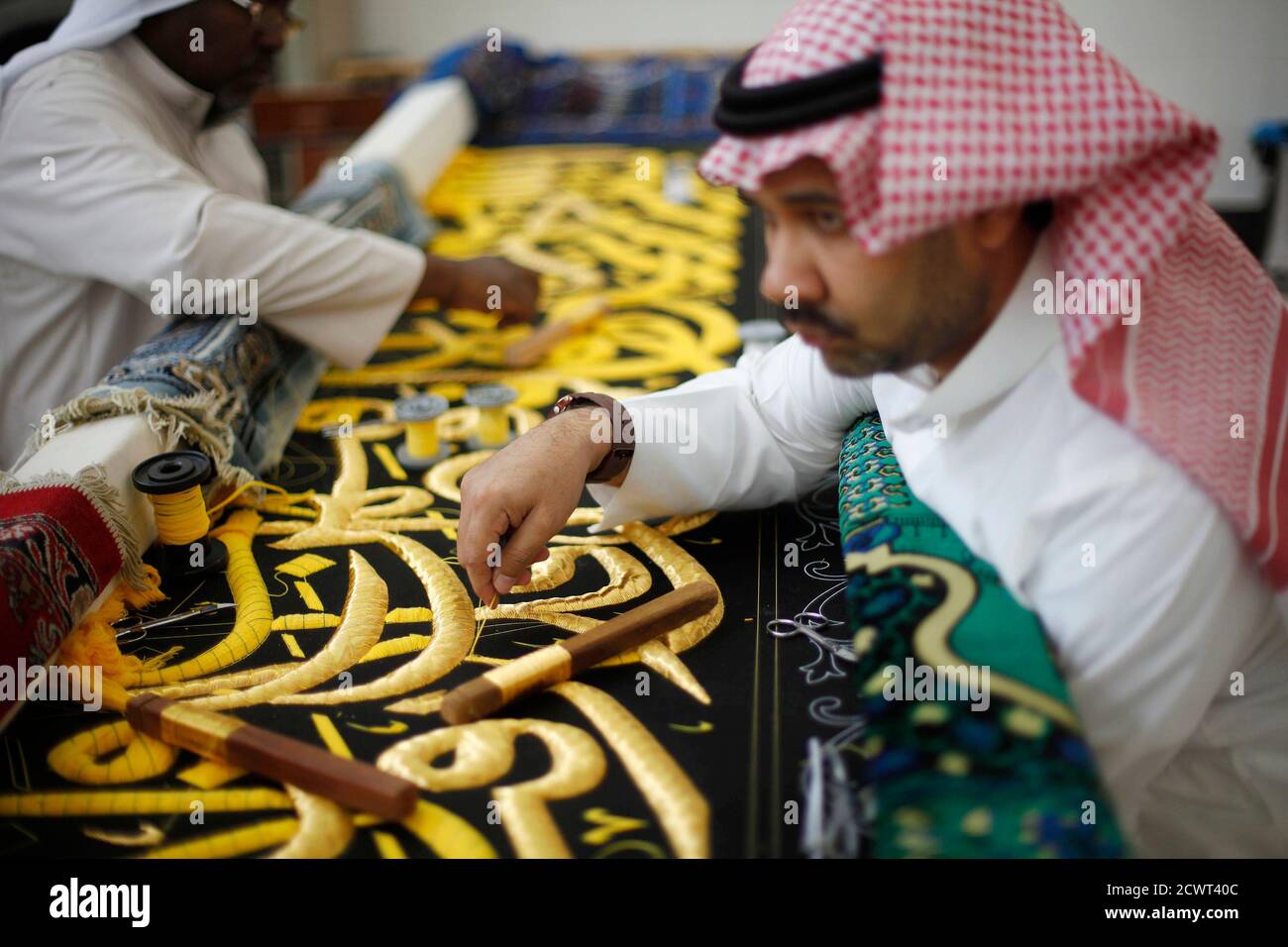 Workers embroider the Kiswa, a silk cloth covering the Holy Kaaba, in