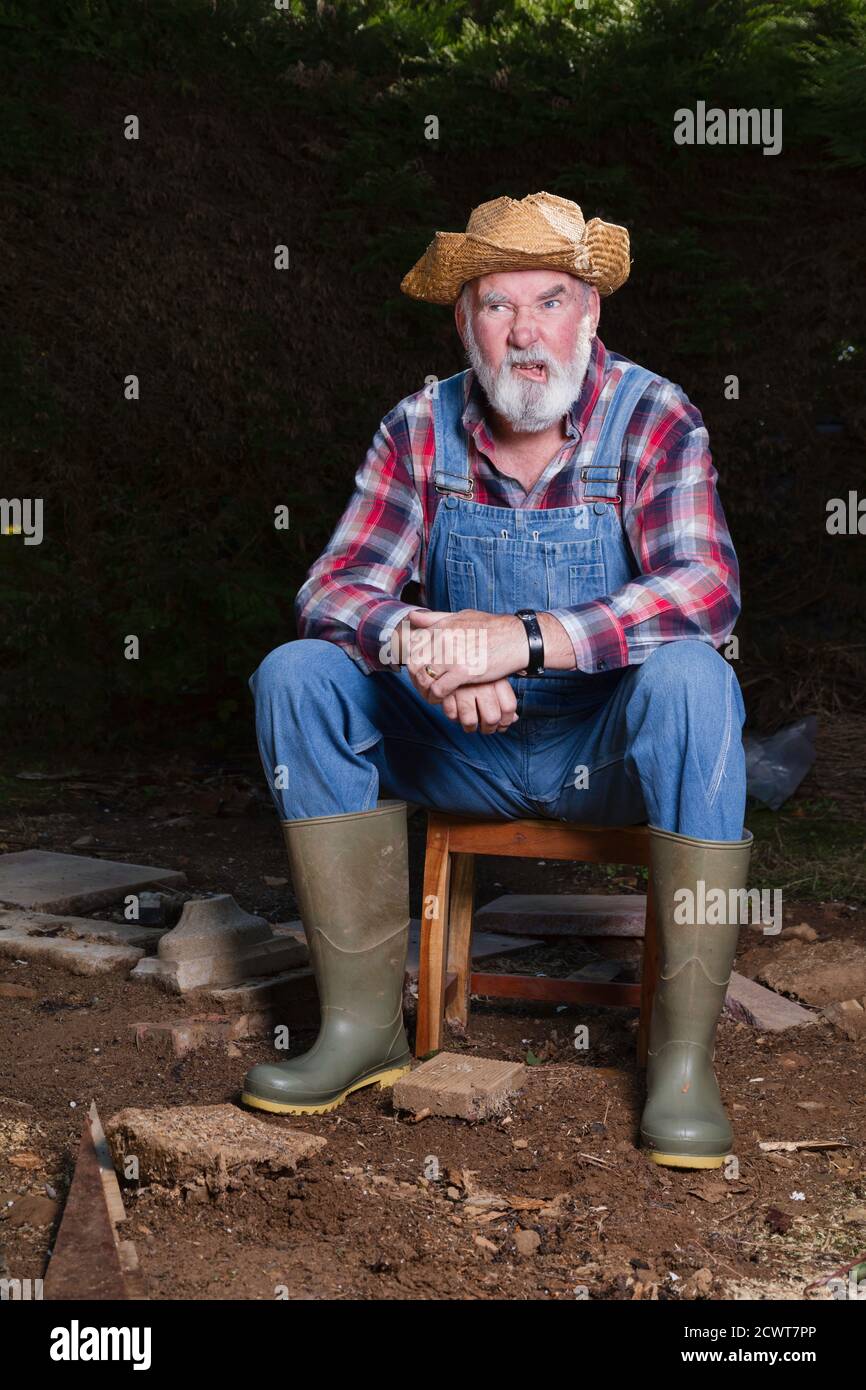 Seventy-year-old, bearded man in dungarees pulling faces. Stock Photo