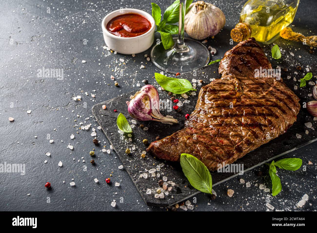 Grilled roasted meat beef steak on black background, with wine, ketchup