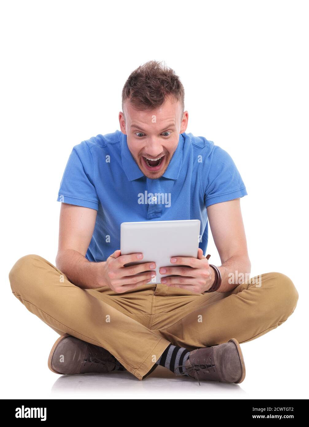 casual young man sitting on the floor with his legs crossed and looking ...