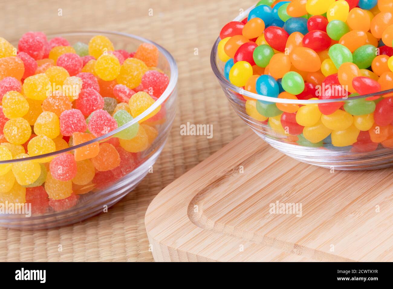 Delicious jelly beans and fruit gum drops in glass bowls on a wooden background Stock Photo