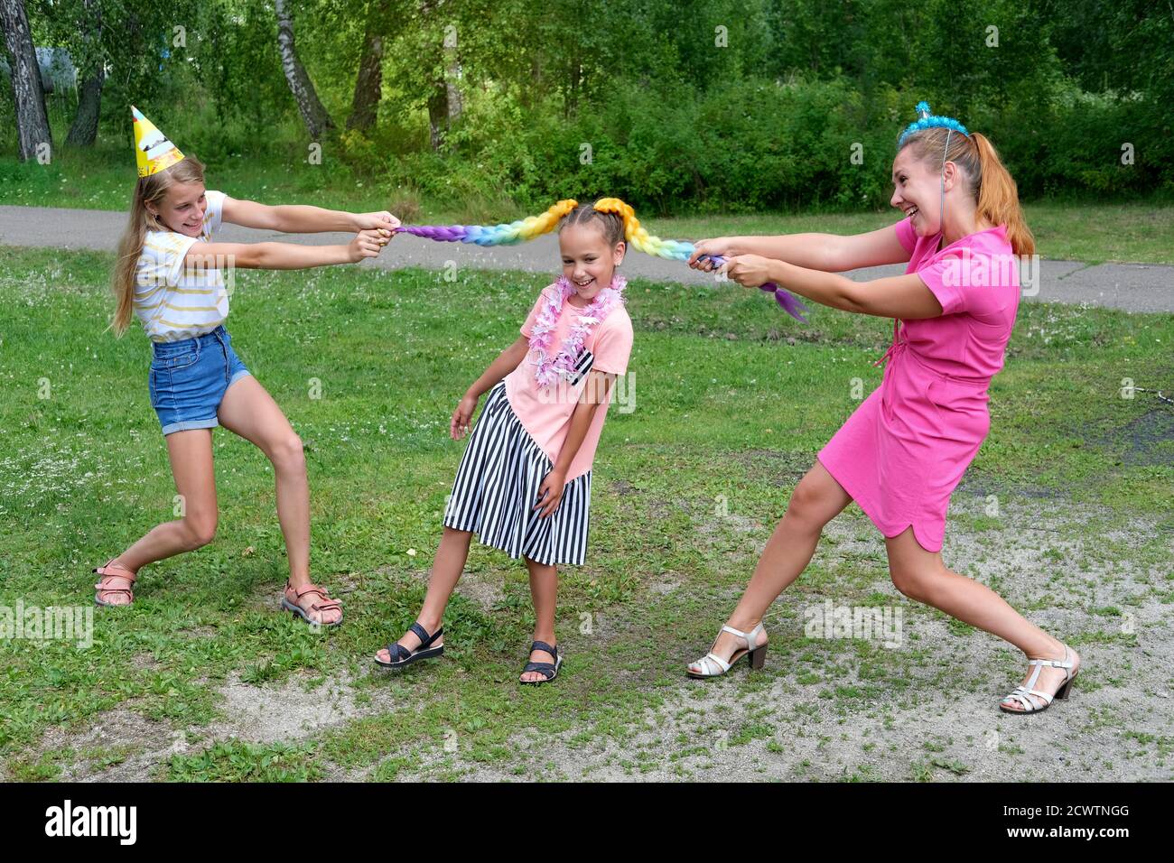 mother and daughters having fun outdoors. pulling girl's braids apart