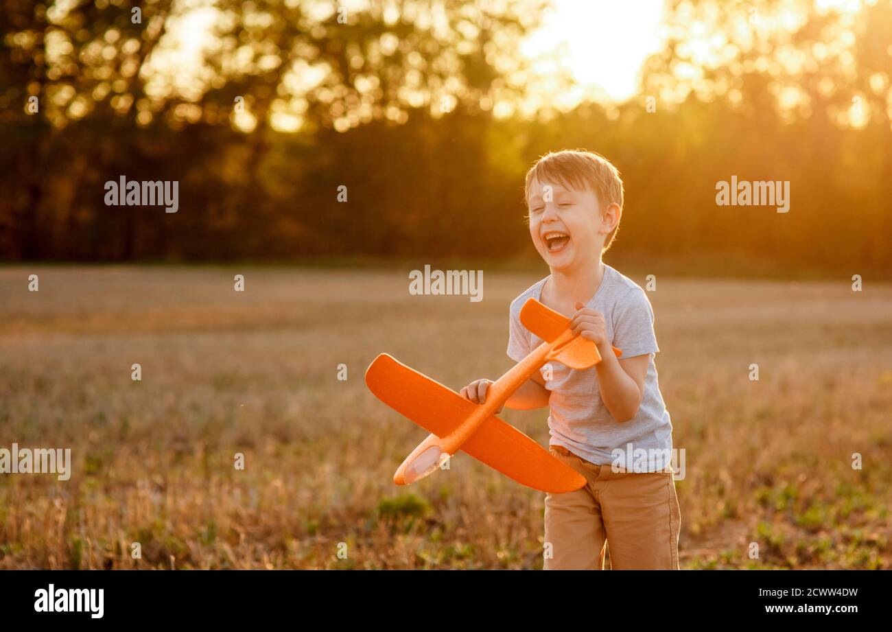 Happy child runs with a toy airplane on a sunset background over a ...
