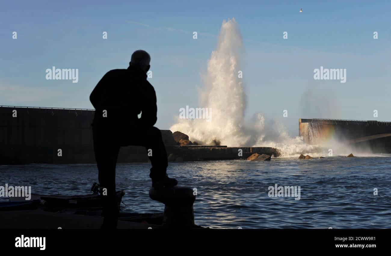 A man watches waves crashing onto a partially destroyed breakwater in Cudillero, northern Spanish region of Asturias, February 2, 2014. Rough weather brought the north of Spain to a standstill with 8 metre (26 ft) high waves causing damage in many coastal towns. REUTERS/Eloy Alonso (SPAIN - Tags: ENVIRONMENT SOCIETY TPX IMAGES OF THE DAY) Stock Photo